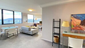 Un salon moderne avec un canapé, une table à manger et des chaises, un téléviseur et un tableau accroché au mur.