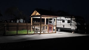 Uma pequena estrutura de madeira com uma mesa e cadeiras, ao lado de uma motorhome grande.