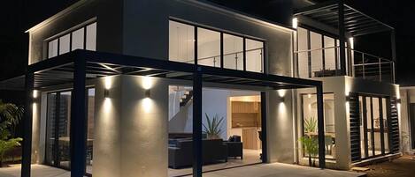 A modern house with a pool, large windows, and a covered outdoor area.