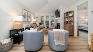 A modern living room with a sofa, armchairs, a coffee table, and a fireplace.