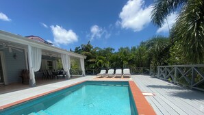 A swimming pool with a wooden deck, lounge chairs, and a covered seating area. - Three Bed Villa with Private Pool Set In Tropical Gardens. (Harbour View Jolly Harbour)