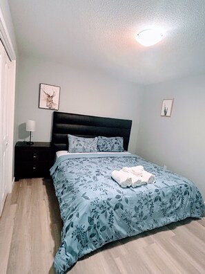 A bedroom with a bed, a nightstand, a lamp, and two wall-mounted pictures.