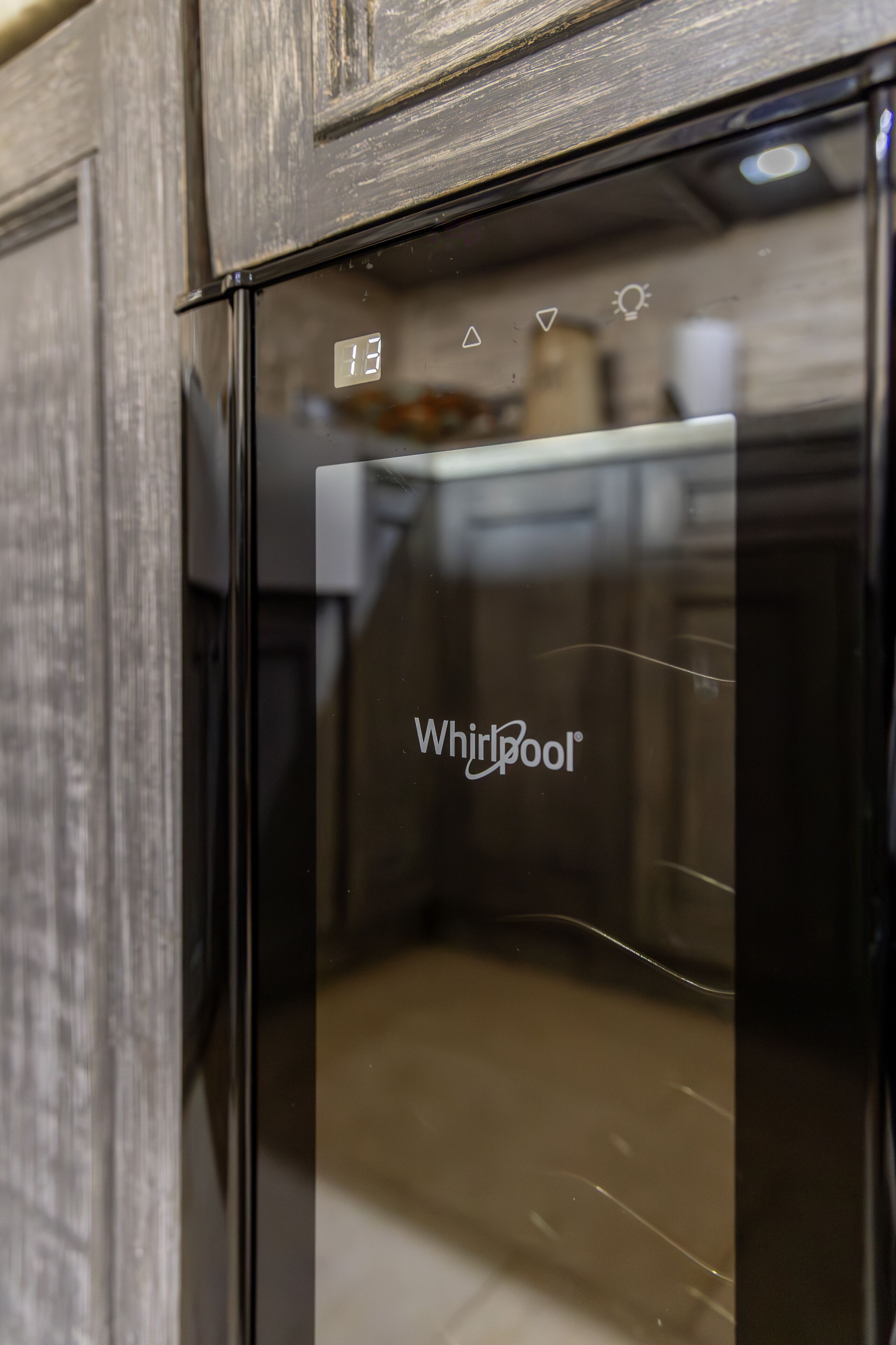 A Whirlpool refrigerator in a kitchen with wooden cabinetry.