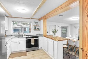 A modern kitchen with white cabinets, a wooden countertop, and a built-in oven. - Central, Cozy Retreat (Vero Beach)