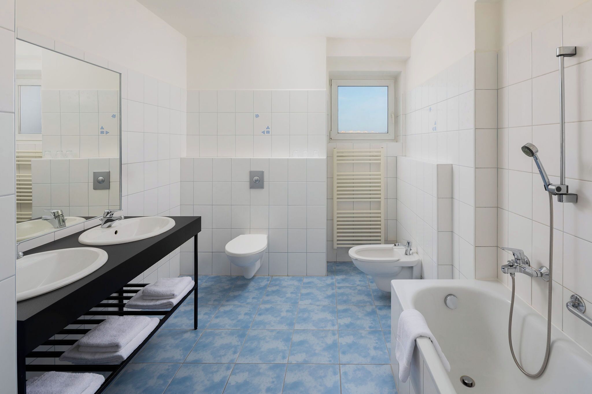 Un baño moderno con dos lavamanos, un inodoro, un bidé y una bañera.