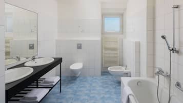 Un baño moderno con dos lavamanos, un inodoro, un bidé y una bañera.