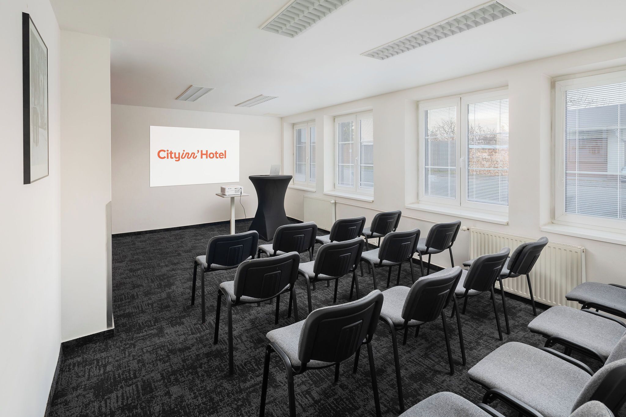 A conference room with rows of chairs, a projector screen, and a whiteboard.