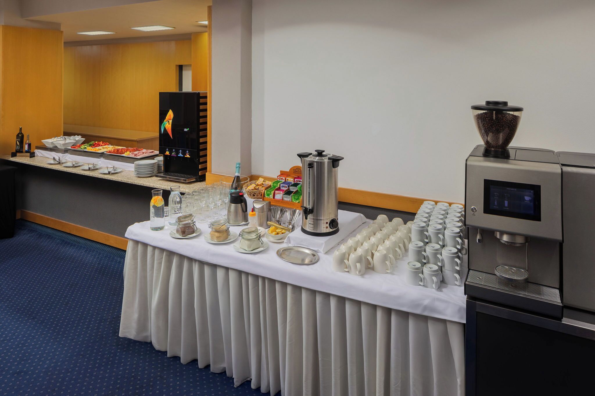 A buffet setup with various food items, a coffee machine, and a beverage dispenser.