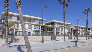 A modern building with multiple balconies and palm trees.