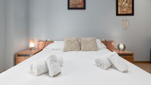 A neatly made bed with two pillows, a bedside lamp, and a decorative wall hanging.