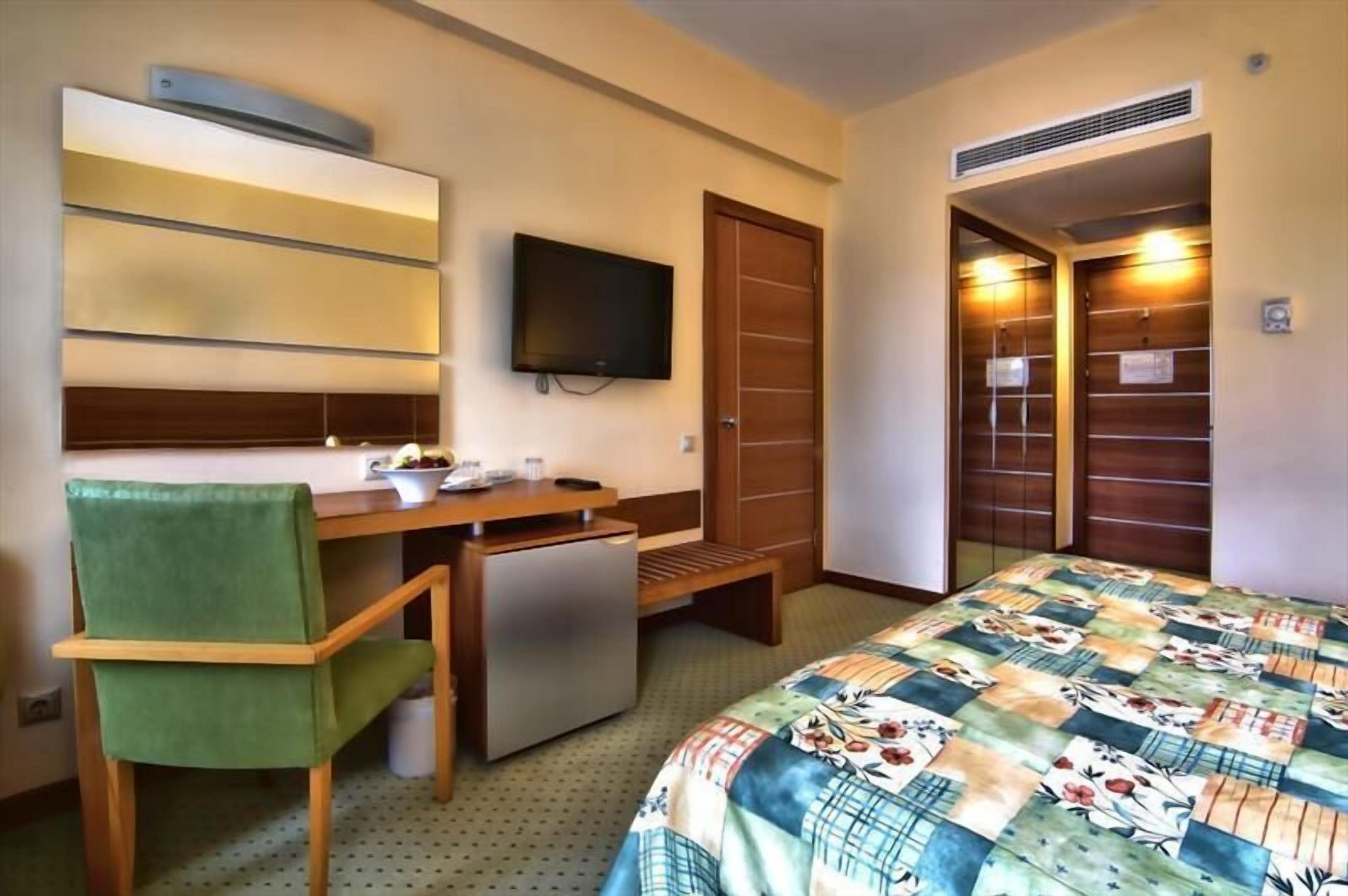 Ein Hotelzimmer mit Bett, Schreibtisch, Stuhl, Fernseher und Kleiderschrank.