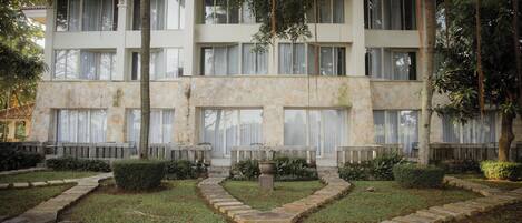 A multi-story building with a stone facade, multiple windows, and a landscaped garden with stone pathways.