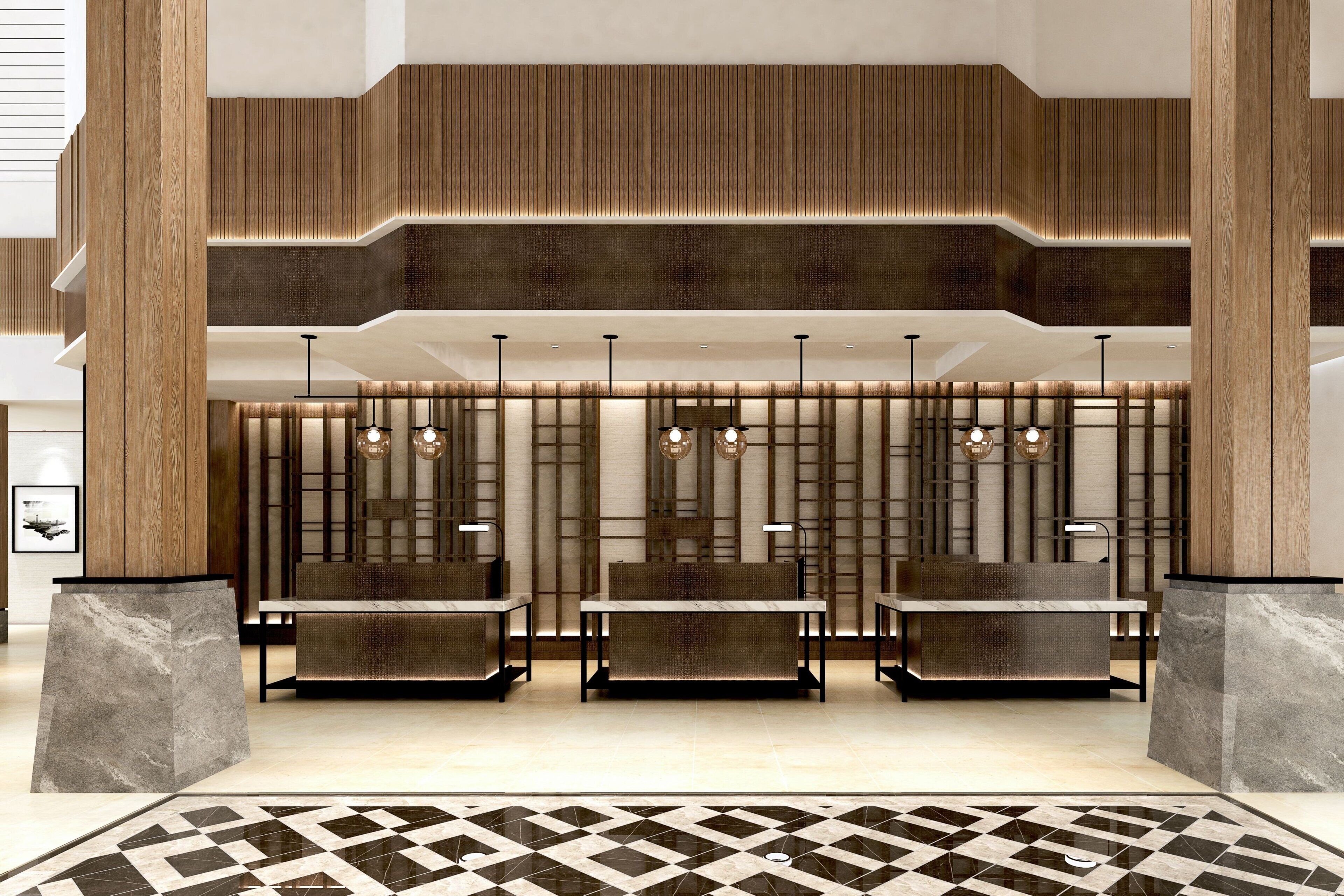 Una hall dal design moderno, con un'area salotto dotata di sedute, tavoli, pavimento decorato e parete rivestita in legno con illuminazione integrata.