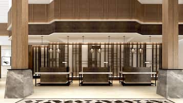 Een moderne lobby met een zithoek met stoelen en tafels, een vloer met een patroon en een houten paneelwand met ingebouwde verlichting.