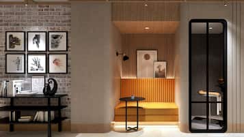 A modern interior with a brick wall, a wooden bench, a round table, and a bookshelf.
