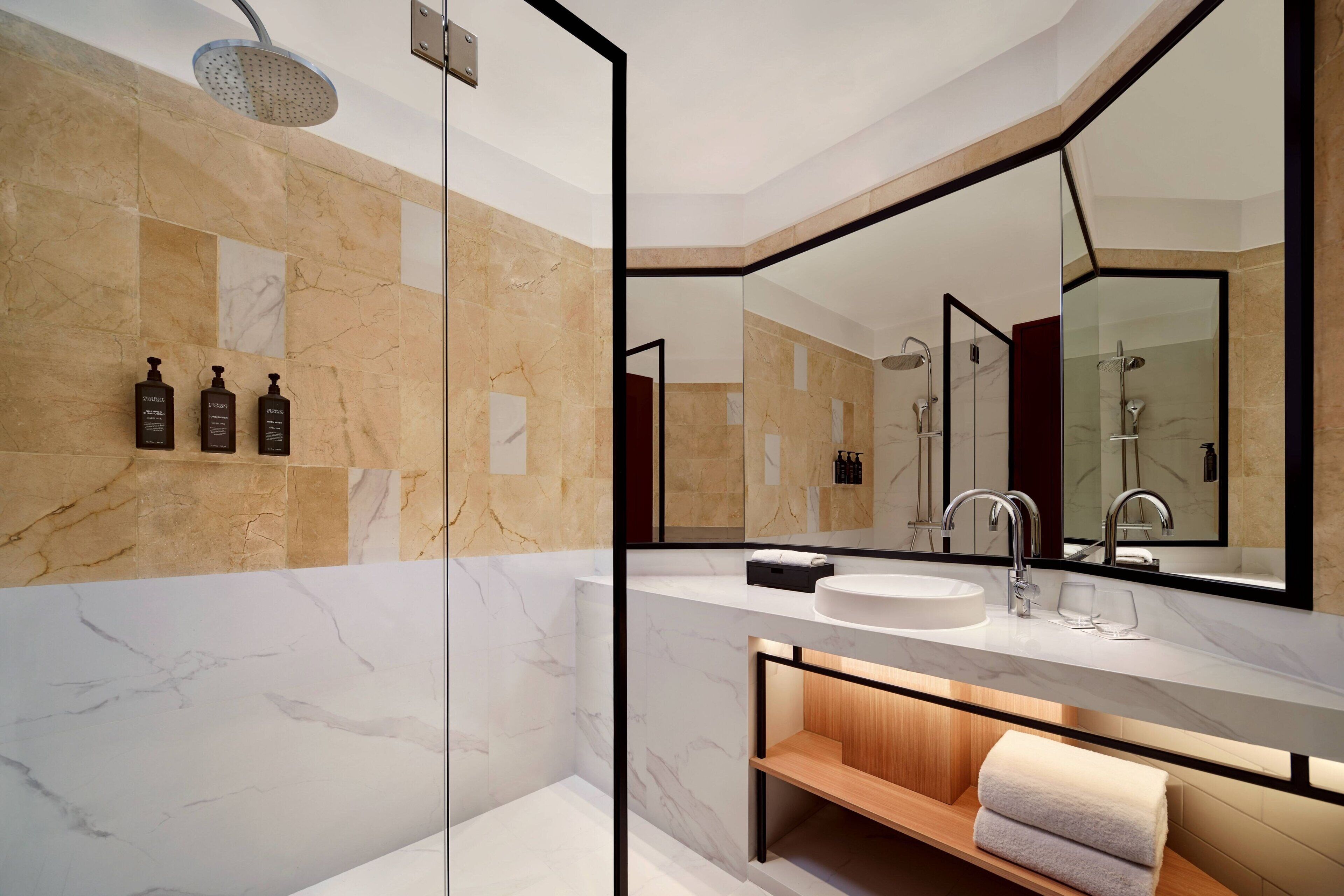 A modern bathroom with a large mirror, a sink, and a shower.