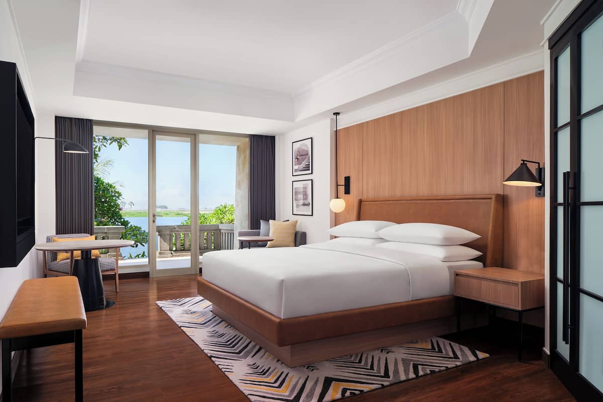 Une chambre d’hôtel moderne dotée d’un grand lit, d’un bureau, d’une chaise et offrant une vue sur l’extérieur.
