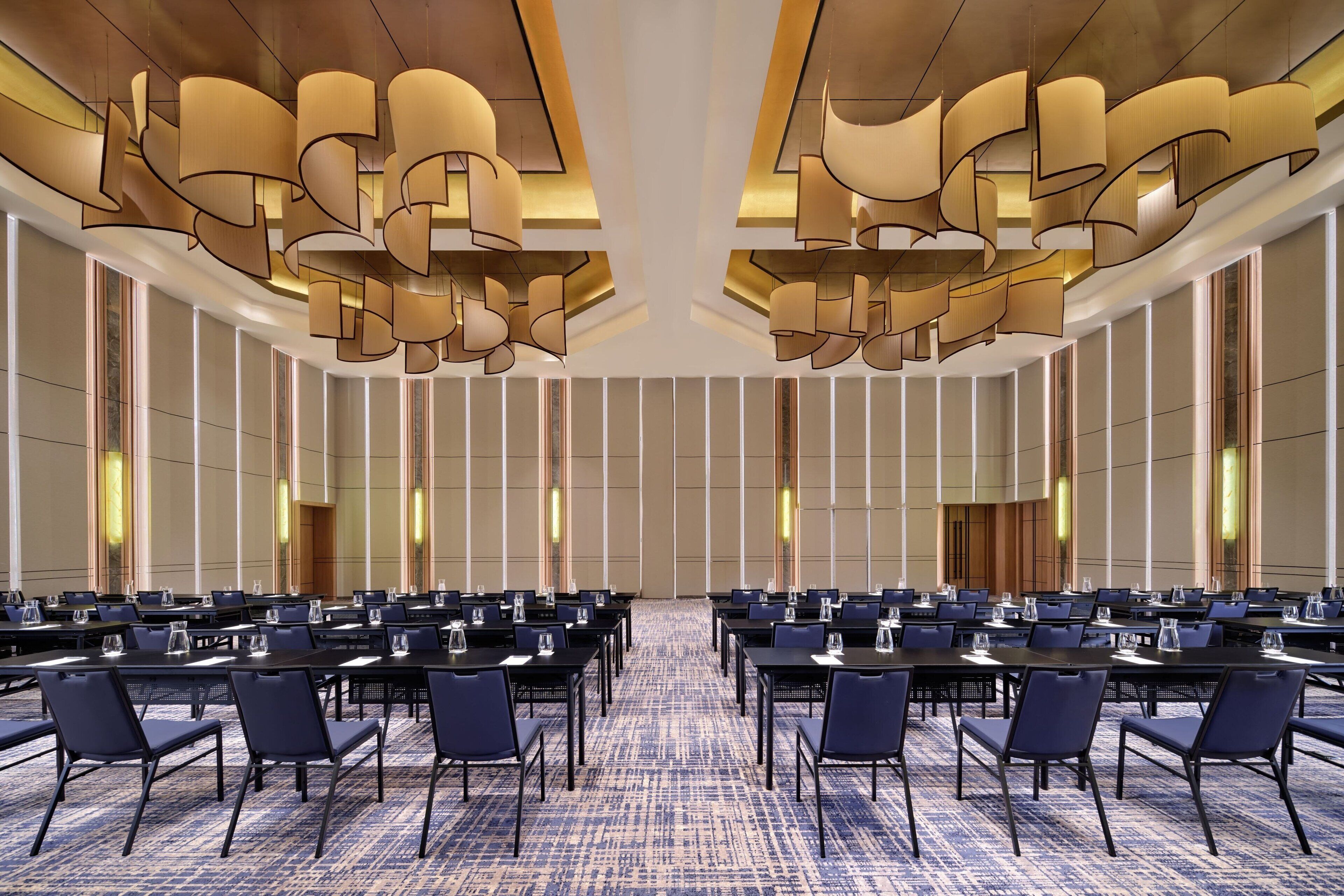 A conference room with multiple tables and chairs, large windows, and a patterned carpet.
