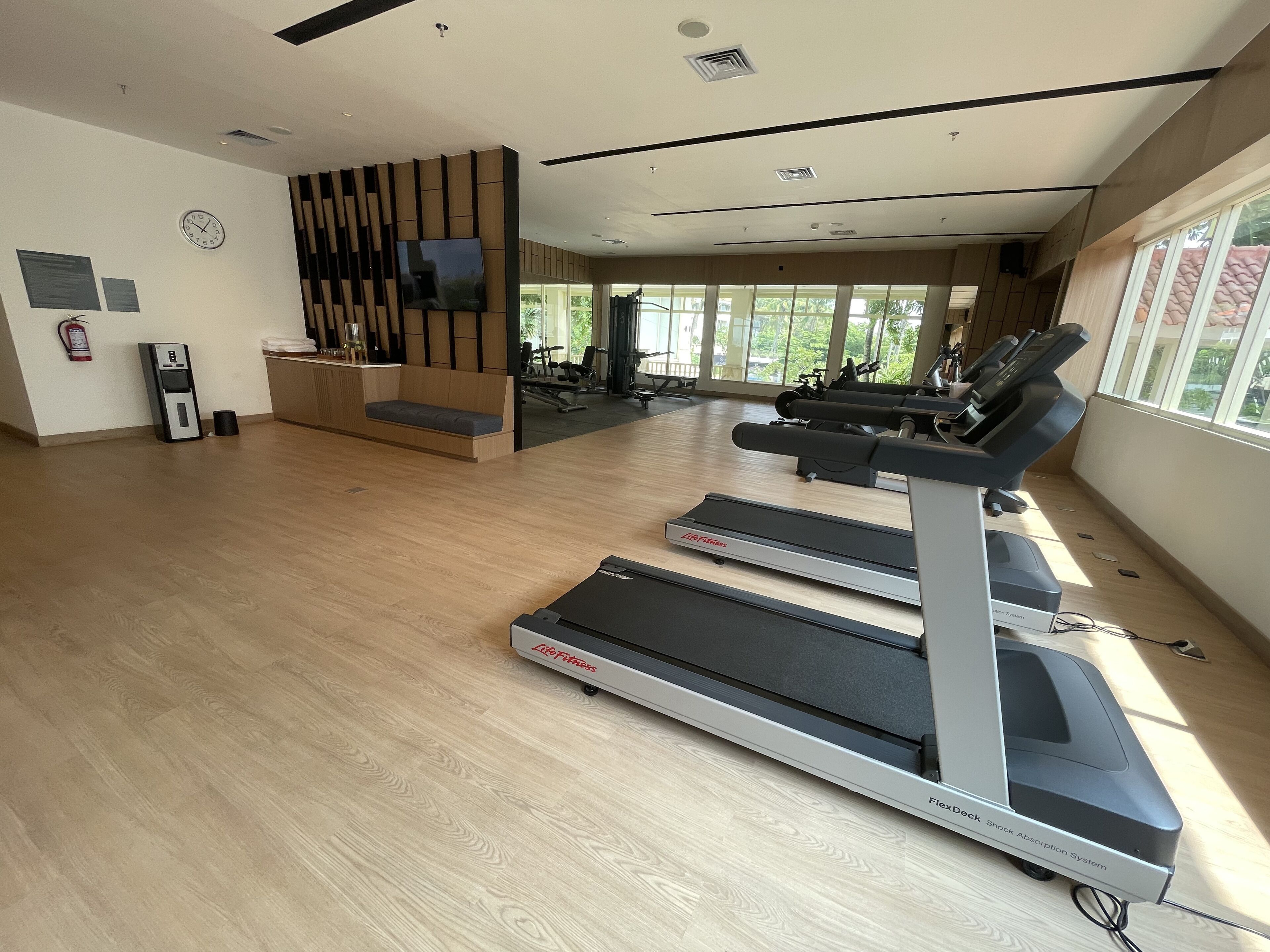 Ein Fitnessraum mit Laufbändern, Wasserspender und Trainingsgeräten.