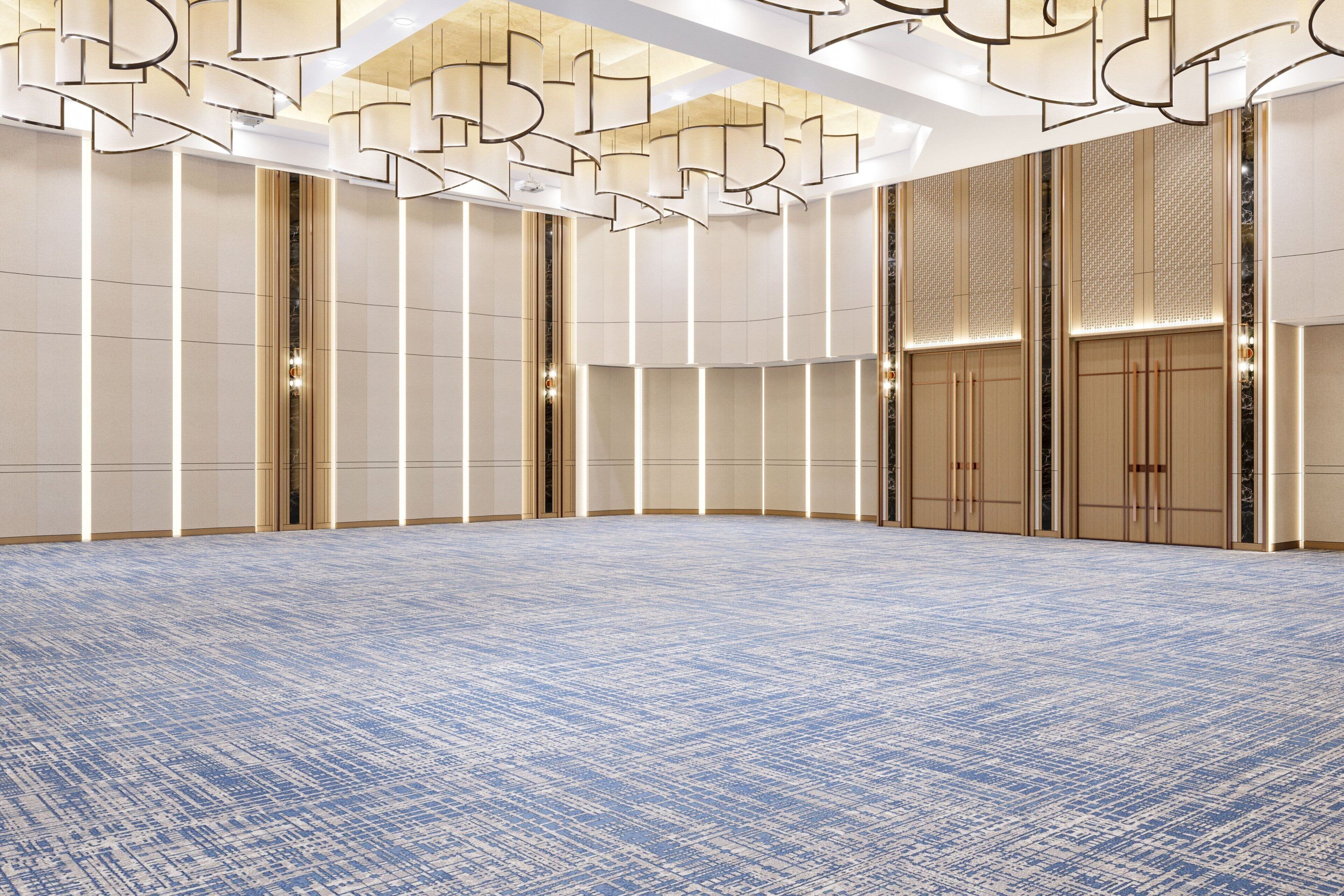 A spacious, well-lit conference room with a patterned carpet, high ceilings, and modern lighting fixtures.