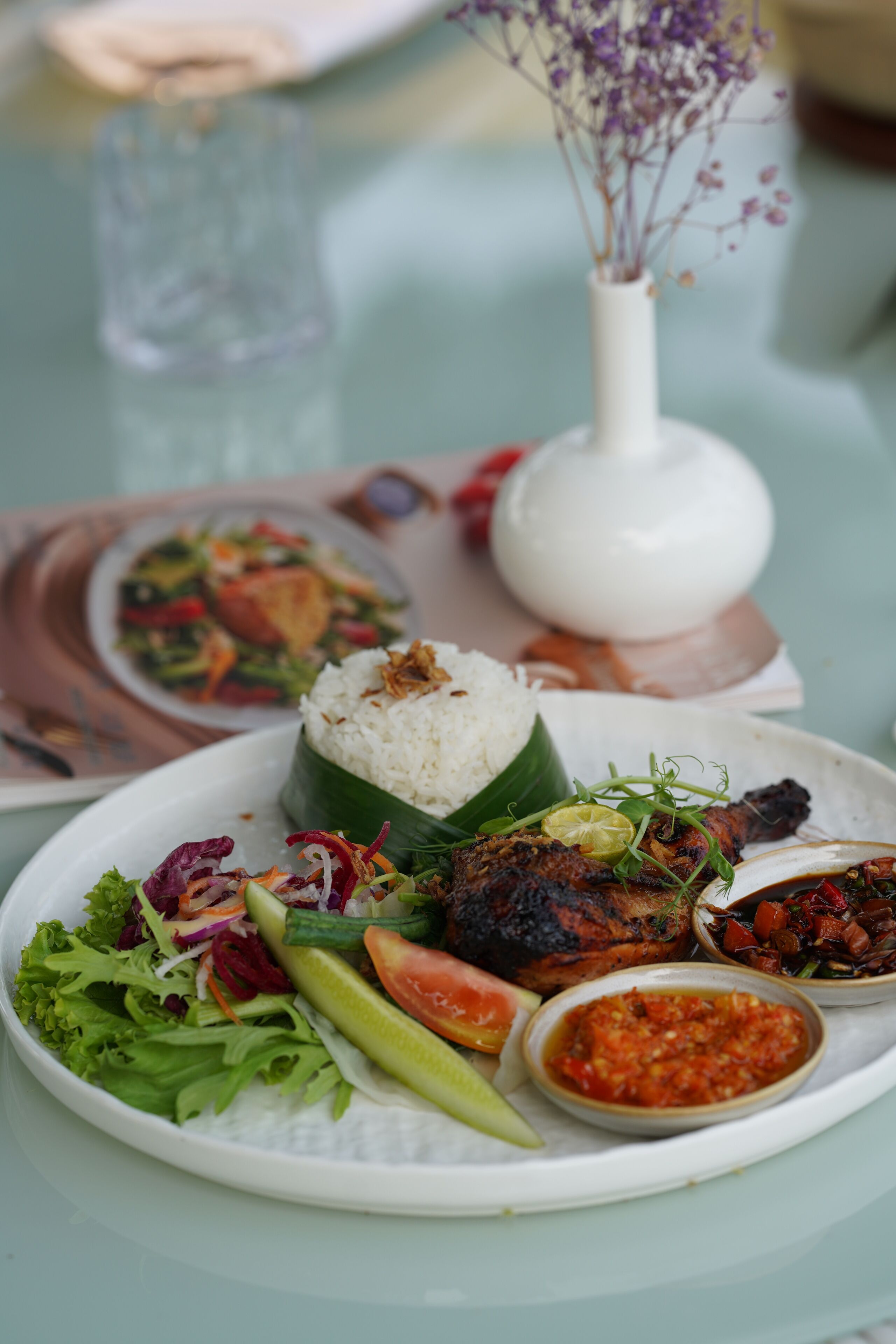 Une assiette remplie de riz, de légumes et de viande, et un verre d’eau posé sur une table.
