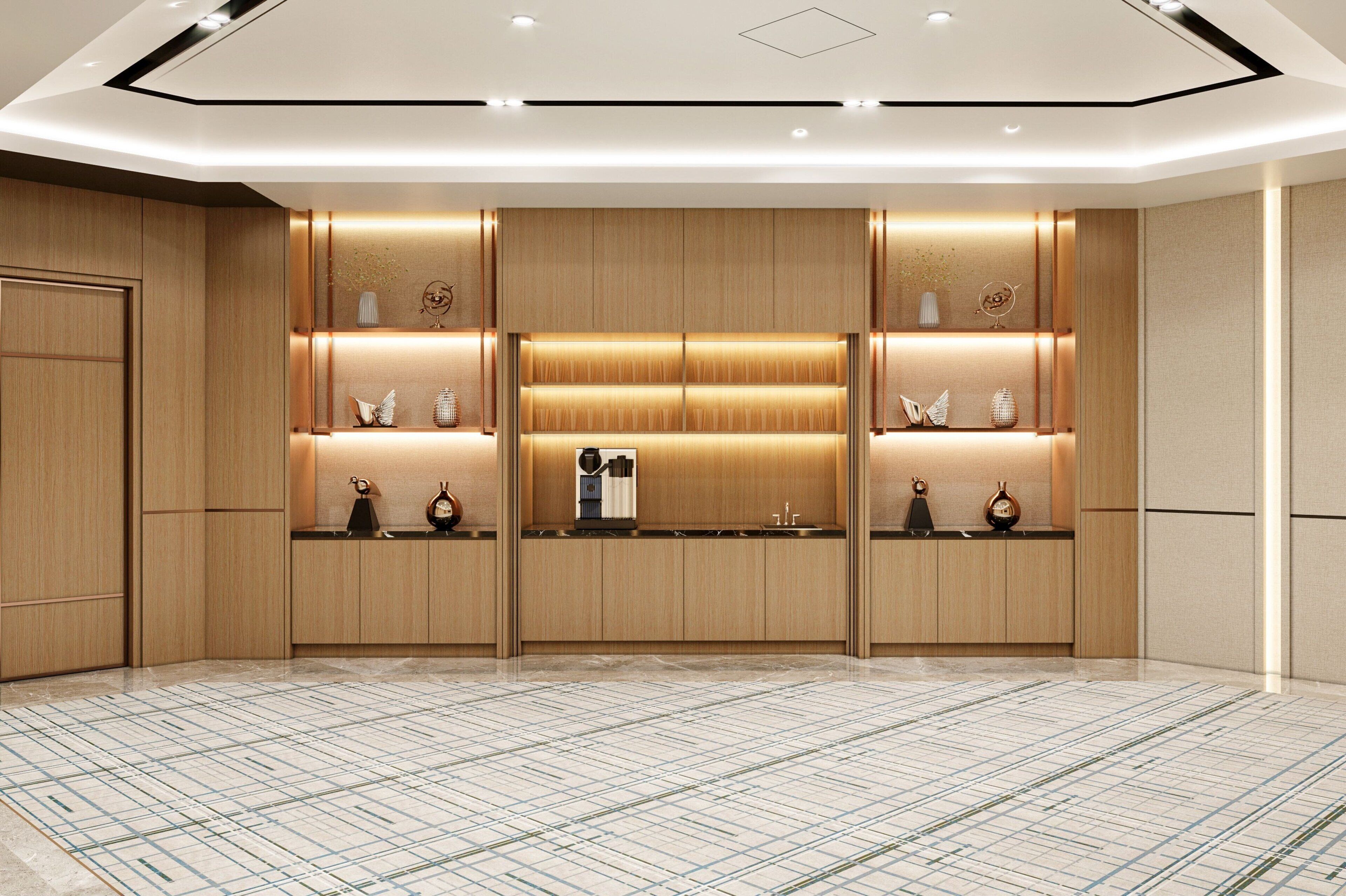 A modern hotel lobby with a central reception desk, wooden paneling, and a patterned floor.