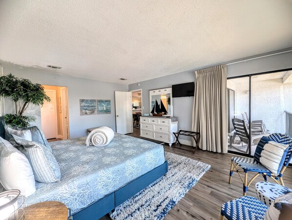 A bedroom with a bed, bedside table, and a large window with curtains. - Villa Largest Pool Views, centrally located (Panama City Beach)