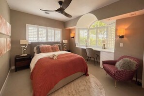 A bedroom with a bed, a desk, a chair, and a ceiling fan.