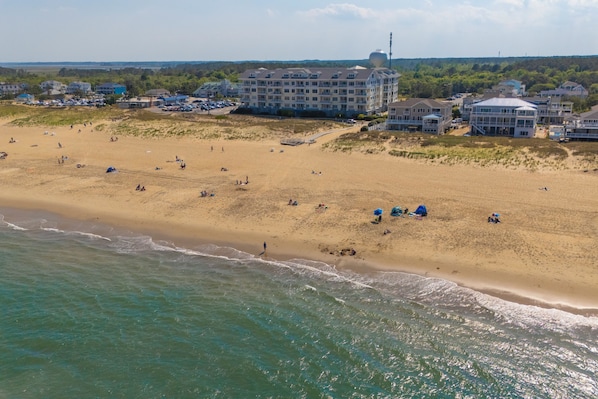Luchtbeeld van een strand met een hotelcomplex op de achtergrond.