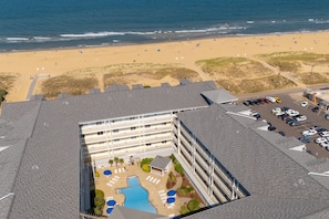 Luchtbeeld van een hotel met zwembad, toegang tot het strand en een parkeerplaats.