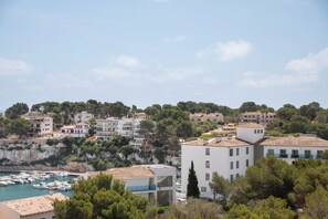 A coastal town with buildings, a marina, and a cliff. - Marina Drach (Manacor)
