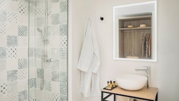 Un baño moderno con ducha de vidrio, lavabo blanco y tocador de madera.