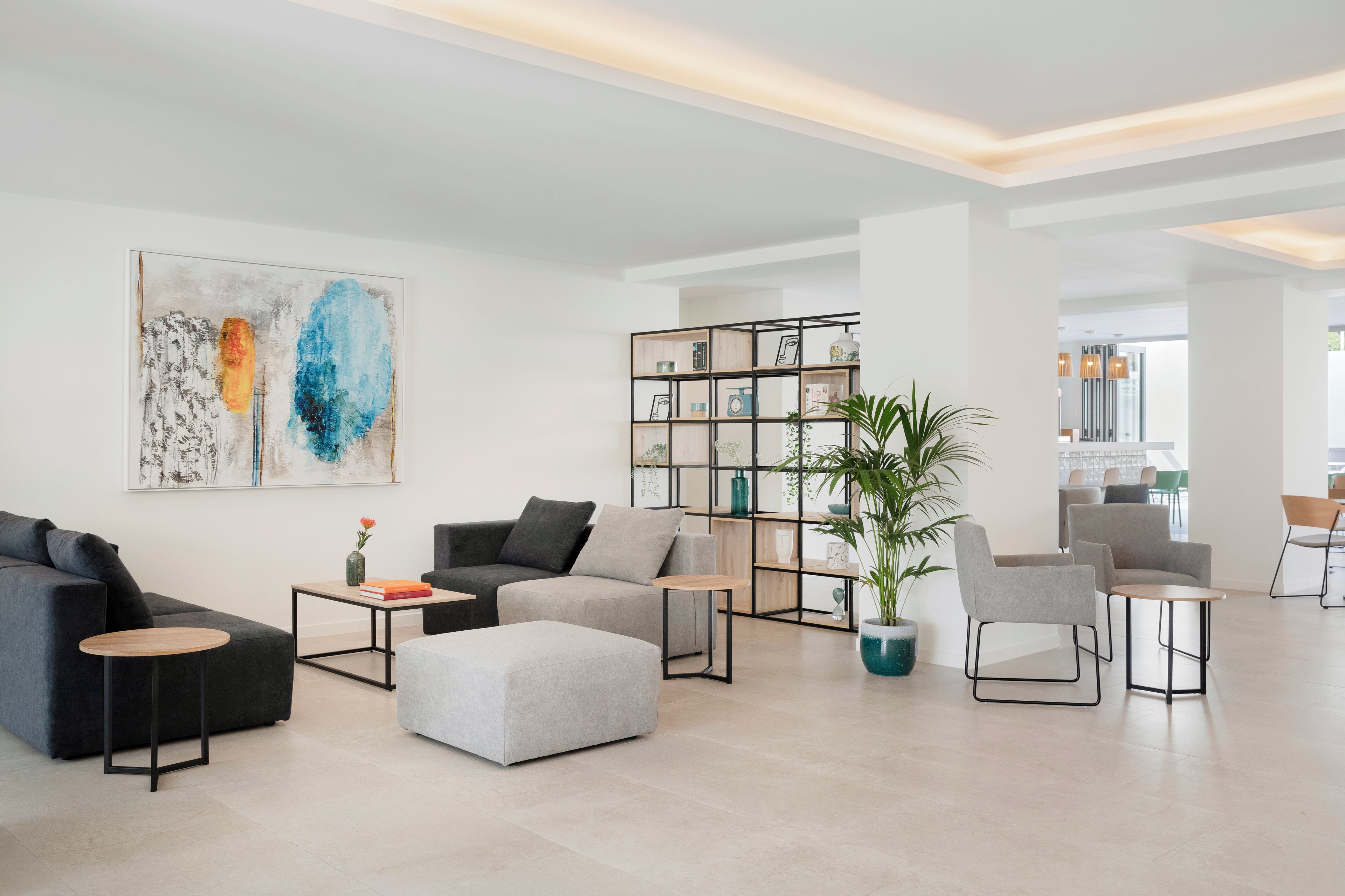 Una sala moderna con un sofá modular, un reposapiés, una mesa de centro y una estantería.