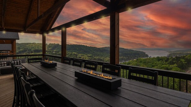 Une terrasse extérieure dotée d’une longue table, de chaises et de foyers intégrés.