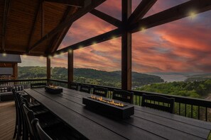 An outdoor deck with a long table, chairs, and built-in fire pits. - Luxe Lodge, HotTub, Theater & Lake View, SDC 3 min (Branson)