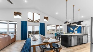 Une cuisine spacieuse dotée d’un îlot central, de grandes fenêtres et offrant une vue sur la mer.