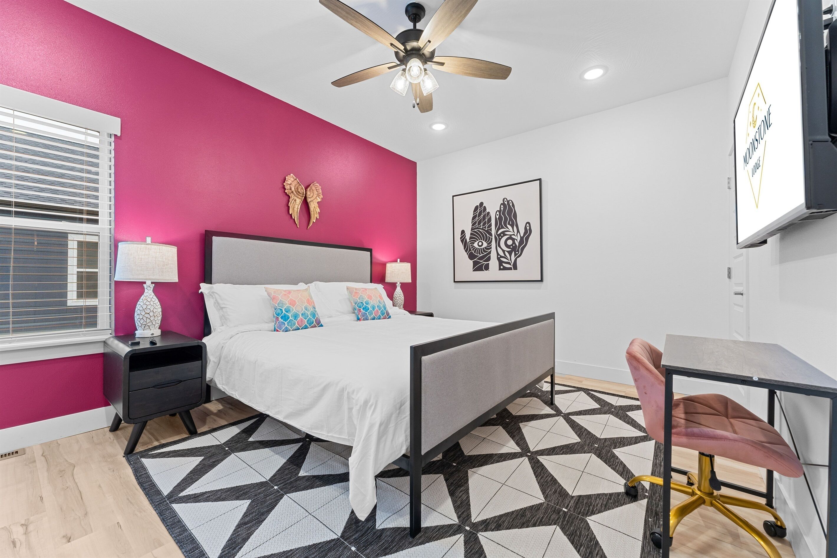A bedroom with a bed, bedside tables, a desk, and a chair.