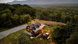 A cabin with a deck and outdoor seating, surrounded by forested hills and mountains. - Luxe Log Cabin, Mountain Views, HotTub, Secluded (Rileyville)