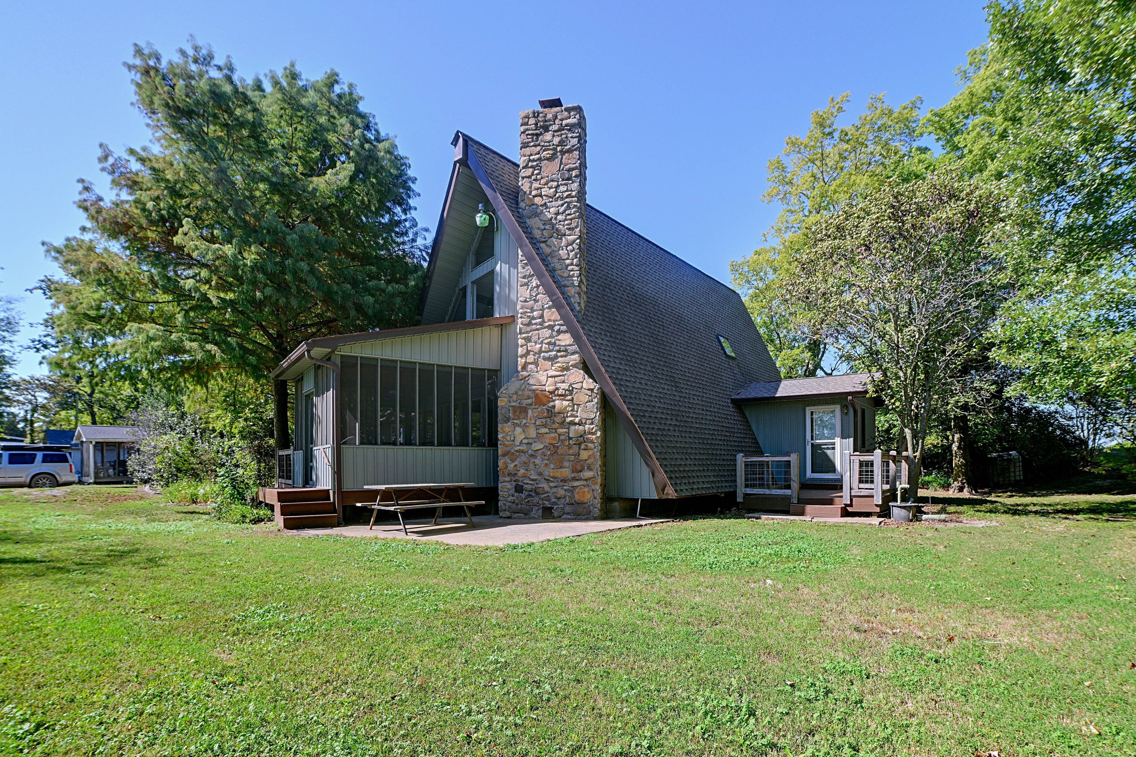 A building with a stone chimney, large windows, and a covered outdoor seating area.