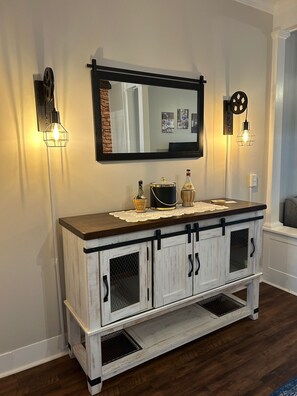 A white wooden console with black handles and a mirror above it.