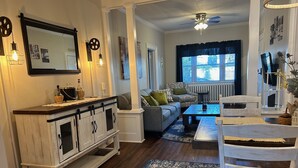 Ein Wohnzimmer mit einem weißen Schrank, einer Couch, einem Couchtisch und einem Esstisch mit Stühlen.