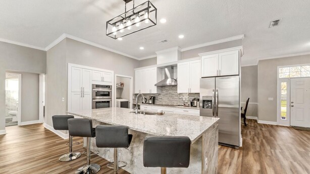 A modern kitchen with a large island, white cabinets, stainless steel appliances, and a herringbone wood floor. - Cozy Restful Memory 3BR@Neptune Beach
 (Jacksonville)