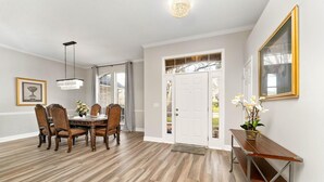 A dining area with a wooden table and chairs, a chandelier, and a door leading outside. - Cozy Restful Memory 3BR@Neptune Beach
 (Jacksonville)