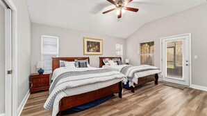 A bedroom with two beds, a ceiling fan, and a door leading to a balcony. - Cozy Restful Memory 3BR@Neptune Beach
 (Jacksonville)