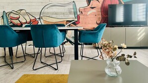 A modern dining area with teal chairs, a table, and a mural on the wall. - Harzfokus - Beautynest Stilvolles Apartment im Zentrum von Wernigerode (Wernigerode)
