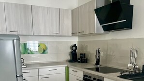 A modern kitchen with white cabinets, a stainless steel refrigerator, a built-in oven, and a coffee maker. - Harzfokus - Beautynest Stilvolles Apartment im Zentrum von Wernigerode (Wernigerode)