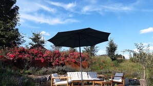 Ein Garten mit Sitzgelegenheiten im Freien, einem großen Sonnenschirm und verschiedenen Pflanzen und Blumen.
