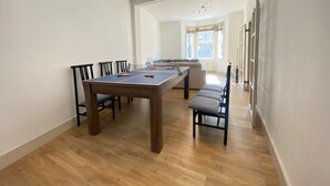 Une pièce spacieuse équipée d’une table de ping-pong, de chaises et d’un canapé.