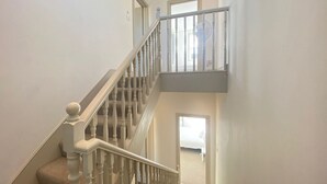 Un escalier avec une rampe blanche et une plateforme recouverte de moquette.