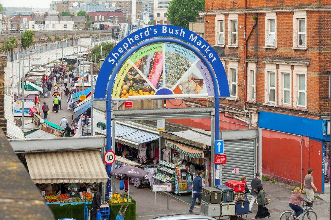 Un vivace mercato con un'imponente insegna ad arco per Shepherd's Bush Market.